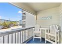 Cozy balcony with white Adirondack chairs and table overlooking the complex and a bright blue sky at 6001 N Ocean Blvd. # 147, North Myrtle Beach, SC 29582