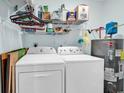 Functional laundry room with modern washer, dryer, water heater, and shelving for extra storage at 8570 Hopkins Circle # D, Surfside Beach, SC 29575