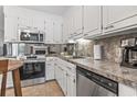 Well-equipped kitchen with stainless steel appliances, white cabinets, and a view into the adjacent living room with fireplace at 86 Beaver Pond Loop # 33, Pawleys Island, SC 29585