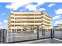 View of the condo's exterior with parking garage, signage and black metal security fence at 1581 S Waccamaw Dr. # 302, Garden City Beach, SC 29576