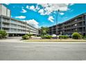 View of the condo complex exterior with parking lot, mature landscaping, and multiple floors with balconies at 210 N Ocean Blvd. # 234, North Myrtle Beach, SC 29582