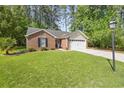 Lovely brick home with a green lawn, bench, and attached two-car garage at 2405 Brick Dr., Longs, SC 29568