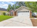 A view of the two-car garage with a brick exterior and a well-kept lawn at 2405 Brick Dr., Longs, SC 29568