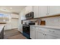 Stylish kitchen boasts white cabinetry, quartz countertops, modern backsplash, and stainless steel appliances at 334 Glacier Way, Conway, SC 29526