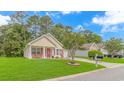 Lovely home with well-manicured lawn, red door and shutters, and a charming front porch seating area at 409 Hunley Ln., Myrtle Beach, SC 29577