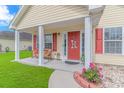 Charming covered front porch with bench seating, decorative red door, and colorful flower bed at 409 Hunley Ln., Myrtle Beach, SC 29577