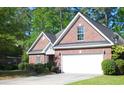 Brick home featuring an attached two-car garage, lush greenery, and a well-maintained lawn at 4266 Arabella Way, Little River, SC 29566