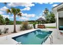 Backyard with a swimming pool, a tiki bar, lush landscaping, and a white fence for privacy at 561 Irees Way, Longs, SC 29568