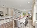 Open-concept dining area with gray chairs, white table, hardwood floors, and view to the living area and kitchen at 886 Cypress Preserve Circle, Longs, SC 29568