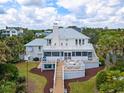 Back exterior view of coastal home featuring a spacious deck, green yard, and lush tropical landscaping at 109 Pioneer Loop, Georgetown, SC 29440