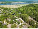 Aerial view of property highlighting wooded lot, pond, in-ground pool and water views in the distance at 12 Gloucester Pl., Pawleys Island, SC 29585