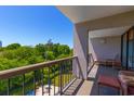 Enjoy an outdoor patio balcony with seating, overlooking mature trees and a community pool at 311 71St Ave. N # 5A, Myrtle Beach, SC 29572