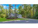 Charming single-story home nestled among mature trees with a well-manicured lawn and attached garage at 5 Old Barge Dr., Pawleys Island, SC 29585