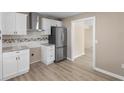 Modern kitchen featuring white cabinets, stainless steel appliances, granite countertops, and wood-look flooring at 509 S Rosemary Ave., Andrews, SC 29510
