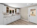 Bright kitchen features white cabinetry, granite countertops, a stainless steel sink, and wood-look flooring at 509 S Rosemary Ave., Andrews, SC 29510