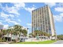 Ocean Forest Plaza condo building exterior view showing balconies and palm trees on a clear, sunny day at 5523 N Ocean Blvd. # 1201, Myrtle Beach, SC 29577