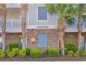 Close-up of condo building detail with signage, sprinker, brick accents, and green shrubs at 5801 Oyster Catcher Dr. # 1621, North Myrtle Beach, SC 29582