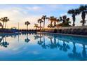 Relaxing pool area with lounge chairs, palm trees, and serene water reflecting the sky at 7100 N Ocean Blvd. # 621, Myrtle Beach, SC 29572