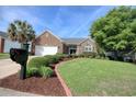Beautifully landscaped brick home featuring a lush green lawn and mature trees at 78 Saltwind Loop, Murrells Inlet, SC 29576