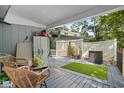 Inviting covered back porch with comfortable wicker seating, potted plants, and an artificial turf rug at 2128 Adams Circle, Little River, SC 29566