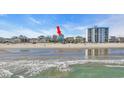 View of a teal beach house from the ocean's edge near a crowded beach and other homes at 2808 N Ocean Blvd., North Myrtle Beach, SC 29582