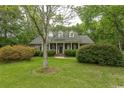 Charming brick home featuring a columned front porch, manicured lawn, and mature landscaping at 4535 Carriage Run Circle, Murrells Inlet, SC 29576