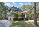 View of the home's side exterior featuring an attached garage, driveway, mature trees, and manicured lawn at 487 Lantana Circle, Georgetown, SC 29440