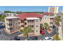 Coastal condos featuring balconies and parking, surrounded by lush palm trees and landscaping at 609 Hillside Dr. S # C-16, North Myrtle Beach, SC 29582