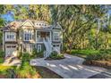 Charming two-story home featuring double garages, mature landscaping, and beautiful surrounding trees at 1033 Tuckers Rd., Pawleys Island, SC 29585