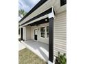 Inviting covered front porch with black pillars, neutral siding and a ceiling fan at 1795 Hemingway St., Conway, SC 29527