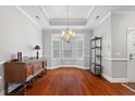 Open dining area boasting a tray ceiling, a bay window, and gleaming hardwood floors at 2993 Moss Bridge Ln., Myrtle Beach, SC 29579