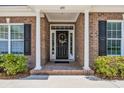 Inviting front entrance with a brick porch and decorative wreath on a black door at 455 Dornoch Dr., Pawleys Island, SC 29585