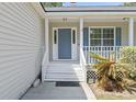 Inviting front porch with a blue door, white railings, and a well-maintained garden at 68 Voyagers Dr., Pawleys Island, SC 29585