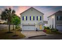 Charming two-story home featuring blue shutters, attached two-car garage, and beautifully landscaped front yard at dusk at 903 Ocean Pines Ct., North Myrtle Beach, SC 29582
