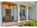 Inviting front porch with seating, a wood ceiling, brick floor, and decoratively potted plants at 25 Northwoods Ct., Pawleys Island, SC 29585