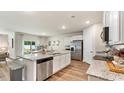 Open-concept kitchen features an island with granite countertops, stainless steel appliances, and white cabinets at 509 Blissful Ln., Little River, SC 29566