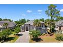 An elevated home with lush landscaping and a grand entrance is surrounded by mature trees and a long driveway at 9060 Abingdon Dr., Myrtle Beach, SC 29579