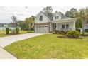 Beautiful single Gathering home with a stone and white exterior, complimented by a green lawn and palm trees at 2928 Moss Bridge Ln., Myrtle Beach, SC 29579