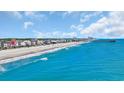 Breathtaking aerial view of the beach with blue water, a fishing pier, and colorful beachfront homes at 324 S Waccamaw Dr., Garden City Beach, SC 29576
