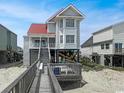 Attractive coastal home with a red metal roof and a wooden walkway leading to the front porch at 324 S Waccamaw Dr., Garden City Beach, SC 29576