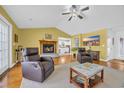 Cozy living room with a brick fireplace, ceiling fan, two leather recliners, and hardwood floors at 4104 Friendfield Trace, Little River, SC 29566