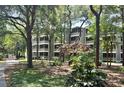 View of the building with screened balconies surrounded by mature trees and landscaping at 415 Ocean Creek Dr. # 2149, Myrtle Beach, SC 29572