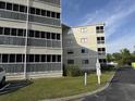 View of condo building exterior with screened balconies, green grass, and blue sky at 4350 Intercoastal Dr. # 2302, Little River, SC 29566