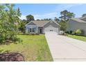 Single-Gathering home featuring a spacious driveway, lush lawn, and charming curb appeal at 5581 Plantersville Pl., Myrtle Beach, SC 29579