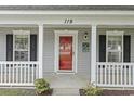 Close-up of the front porch, showcasing the bright red door, white pillars, and detailed trim at 119 Pickerel Blvd., Longs, SC 29568