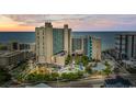 An aerial view showcases the oceanfront resort with its colorful pools and a modern architectural design at sunset at 205 74Th Ave. N # 1104, Myrtle Beach, SC 29572