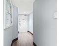 Bright hallway featuring wood floors, light blue walls, and a door, enhanced by a simple painting at 205 74Th Ave. N # 1104, Myrtle Beach, SC 29572