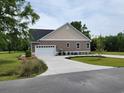 Home showcasing its clean driveway leading to an attached garage, surrounded by lush greenery at 214 Carolina Dr., Loris, SC 29569