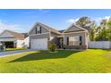 Attractive home showcasing manicured lawn, gray siding, brick accents, and a two-car garage at 263 Lakota Loop, Longs, SC 29568