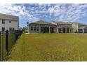 Large grassy backyard featuring a screened porch and a black iron fence at 428 Calhoun Falls Dr., Myrtle Beach, SC 29579
